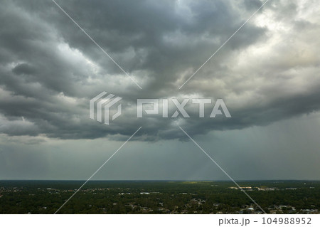 Dark stormy clouds forming on gloomy sky before heavy rainfall over suburban town area Dark stormy clouds forming on gloomy sky before heavy rainfall over suburban town area 104988952