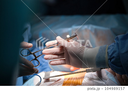Closeup of professional doctor hands operating a patient during open heart surgery in surgical room. Healthcare and medical intervention concept 104989157
