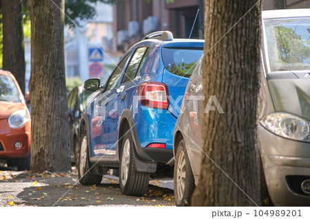 City traffic with many cars parked in line on street side 104989201