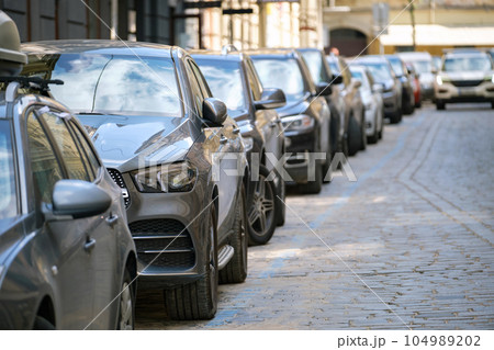 City traffic with cars parked in line on street side. 104989202