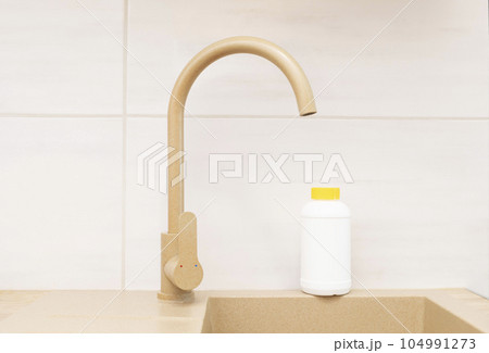 Pipe Drain Granules in White Plastic Bottle With Yellow Cap On Kitchen Sink In Cook Room. Clog Cleaner, Housework Help. Cleaning enzymes, Prevention of Blockages In Traps. Horizontal plane Pipe Drain Granules in White Plastic Bottle With Yellow Cap On Kitchen Sink In Cook Room. Clog Cleaner, Housework Help. Cleaning enzymes, Prevention of Blockages In Traps. Horizontal plane 104991273