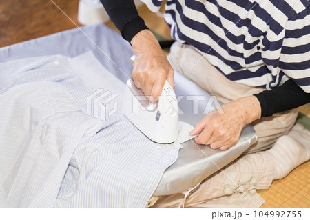 衣類スチーマーでカッターシャツのアイロンを掛けるシニア女性 104992755