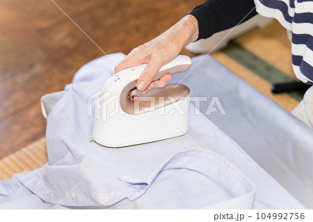 衣類スチーマーでカッターシャツのアイロンを掛けるシニア女性 衣類スチーマーでカッターシャツのアイロンを掛けるシニア女性 104992756