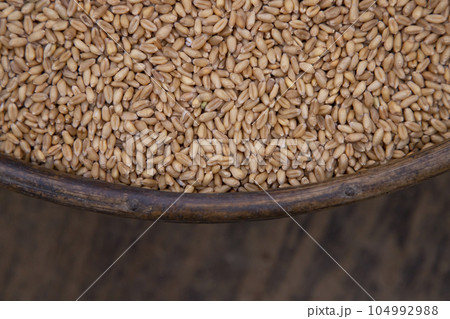 Wheat grains in a bowl on a wooden background, top view 104992988