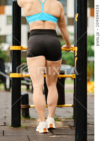 Back view of muscular legs of female bodybuilder on sports ground 104994039