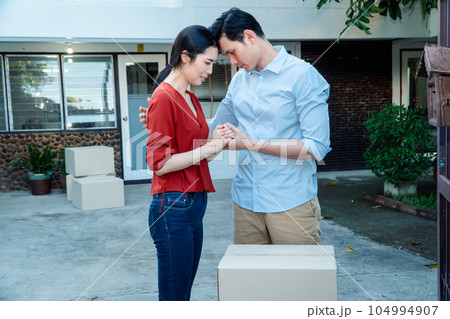 Man comforting his wife and woman hugging her husband and cry in front of the house and full of cardboard boxes during the transport in move out day, moving home concept Man comforting his wife and woman hugging her husband and cry in front of the house and full of cardboard boxes during the transport in move out day, moving home concept 104994907