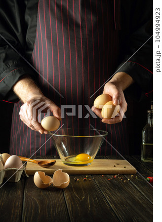 The chef prepares an egg omelette for breakfast. Working environment in a restaurant kitchen. Copy space The chef prepares an egg omelette for breakfast. Working environment in a restaurant kitchen. Copy space 104994923