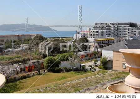 明石海峡大橋を五色塚古墳から山陽電鉄霞ヶ丘駅東側の山陽電鉄6000系越しに望む 104994988
