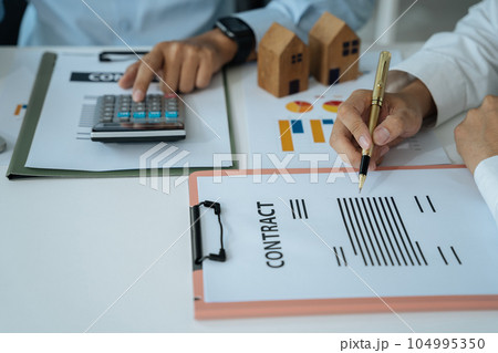 Buying a home or insurance deal, an insurance agent pointing a pen to those interested in renting a house, a contract, signing an Home buying agreement in office Buying a home or insurance deal, an insurance agent pointing a pen to those interested in renting a house, a contract, signing an Home buying agreement in office 104995350