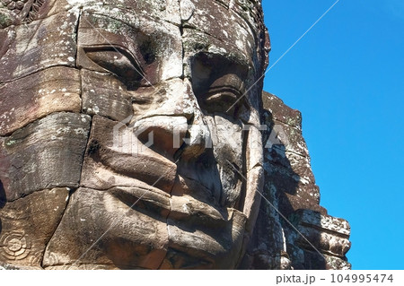 The art of ancient Cambodia represented by a stone face sculpture with a smile. 104995474