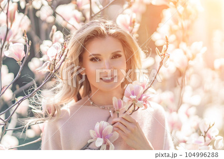 Magnolia woman portrait. Happy middle aged woman enjoying the smell in a blooming spring garden. Beautiful magnolia bushes, large flowers. Magnolia woman portrait. Happy middle aged woman enjoying the smell in a blooming spring garden. Beautiful magnolia bushes, large flowers. 104996288