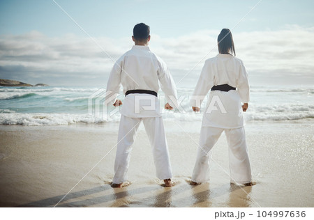Training with a view. Rearview shot of two unrecognizable martial artists practicing karate on the beach. Training with a view. Rearview shot of two unrecognizable martial artists practicing karate on the beach. 104997636