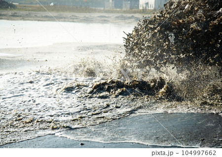 Pollution, sewer and waste in water to ocean from industrial for construction, pipeline and danger. Environment, texture and industry with wave from sewage on shoreline for stream, foam and mud 104997662