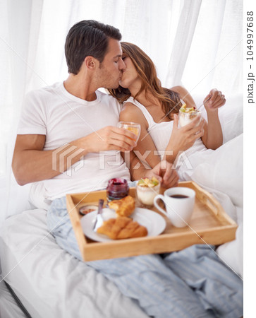 Bedroom breakfast, love kiss and couple relax with morning food, bond and enjoy quality time together in Toronto Canada. Marriage romance, room service meal and people on hotel bed for Valentines Day 104997688