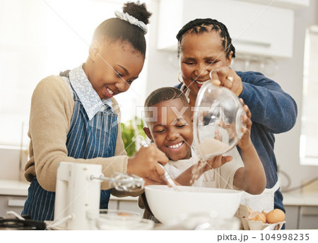 Happy family, grandma teaching kids baking and learning baker skill in kitchen with help and support. Old woman, girl and boy with flour, development for growth and bake with ingredients at home Happy family, grandma teaching kids baking and learning baker skill in kitchen with help and support. Old woman, girl and boy with flour, development for growth and bake with ingredients at home 104998235