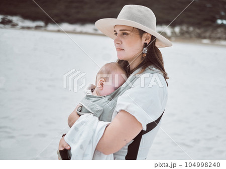 Find a break at the beach. Shot of a young mother holding her baby while at the beach. Find a break at the beach. Shot of a young mother holding her baby while at the beach. 104998240