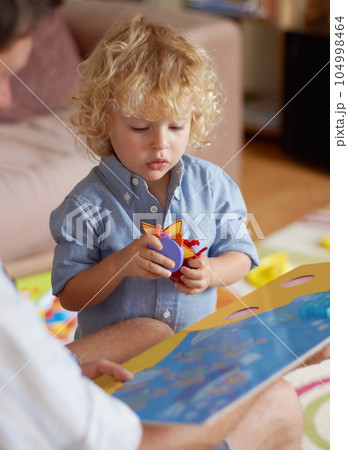 Father with boy kid, reading book for education and development, spending quality time together at home. Family, teaching and learning with man and child bonding, picture story with toys for growth Father with boy kid, reading book for education and development, spending quality time together at home. Family, teaching and learning with man and child bonding, picture story with toys for growth 104998464