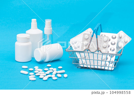 Pills and Capsules in Shopping Basket on Blue Background Pills and Capsules in Shopping Basket on Blue Background 104998558