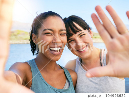 Portrait of two smiling friends taking selfies together for social media on a lake over summer break. Smiling happy women bonding and hugging outside in nature. Embracing and having fun on weekend Portrait of two smiling friends taking selfies together for social media on a lake over summer break. Smiling happy women bonding and hugging outside in nature. Embracing and having fun on weekend 104998622