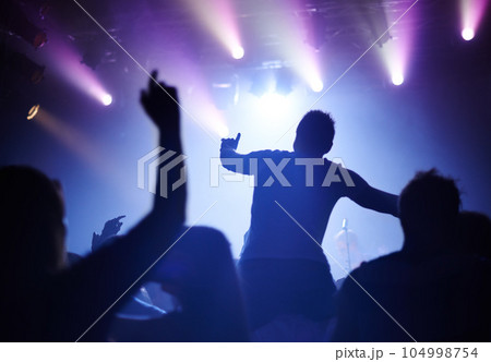 Rock concert, dance and party crowd with disco lighting and people back with dancing. Silhouette, audience and night festival event with performance and group listening and watching a band music Rock concert, dance and party crowd with disco lighting and people back with dancing. Silhouette, audience and night festival event with performance and group listening and watching a band music 104998754