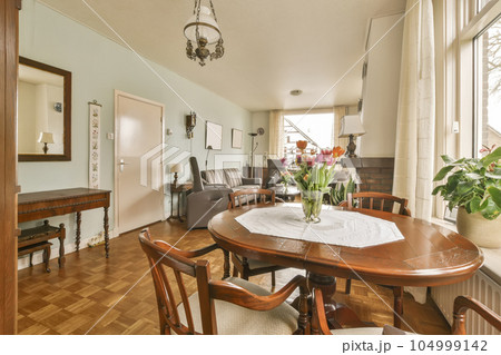a dining room with wood flooring and wooden table in front of large window looking out onto the living room a dining room with wood flooring and wooden table in front of large window looking out onto the living room 104999142