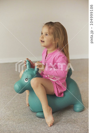 Adorable child on a toy horse at home Adorable child on a toy horse at home 104999186