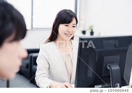 オフィスで笑顔で仕事をするオフィスワーカー 105000848