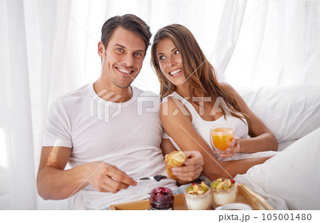 Breakfast in bed, portrait and morning couple relax with food, love bond and enjoy quality time together. Marriage romance, meal or happy people in hotel bedroom for Valentines Day in Toronto Canada 105001480