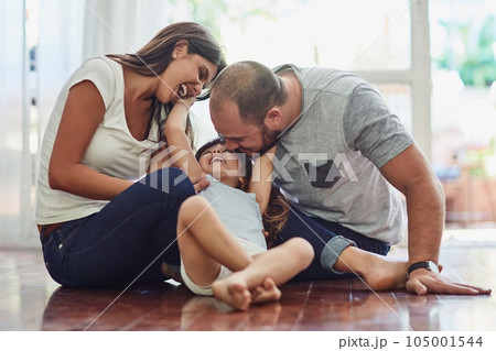 Family, parents with their daughter playing and happy in living room of their home. Love or care, support and cheerful or happy people spend quality or bonding time together on floor at their house. 105001544