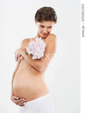Pregnancy, abdomen and woman with flowers for motherhood on a white background in studio. Smile, stomach and pregnant woman with a bouquet of Deutzia for love of a child on a studio background 105001563