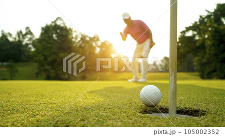 Golfer action to win after long putting golf ball in to the hole. Golfer action to win after long putting golf ball in to the hole. 105002352