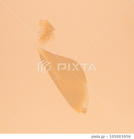 Smear of brown cream for face and body on a sand color background 105003956