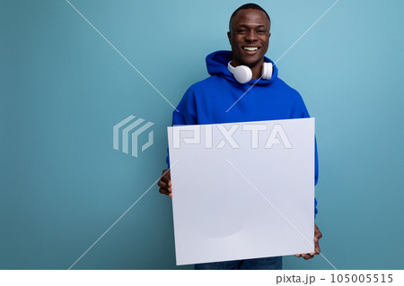 positive young african man presenting a project on a white sheet with a large flyer layout on the 105005515