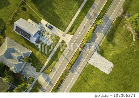 Aerial view of street traffic with driving cars in small town America suburban landscape with private homes between green palm trees in Florida quiet residential area Aerial view of street traffic with driving cars in small town America suburban landscape with private homes between green palm trees in Florida quiet residential area 105006271