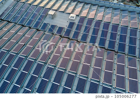 Aerial view of solar power plant with blue photovoltaic panels mounted on industrial building roof for producing green ecological electricity. Production of sustainable energy concept Aerial view of solar power plant with blue photovoltaic panels mounted on industrial building roof for producing green ecological electricity. Production of sustainable energy concept 105006277