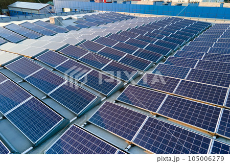 Aerial view of solar power plant with blue photovoltaic panels mounted on industrial building roof for producing green ecological electricity. Production of sustainable energy concept 105006279
