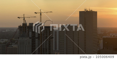 Aerial view of new developing residense in american urban area at sunset. Tower cranes at industrial construction site in Miami, Florida. Concept of housing growth in the USA Aerial view of new developing residense in american urban area at sunset. Tower cranes at industrial construction site in Miami, Florida. Concept of housing growth in the USA 105006409