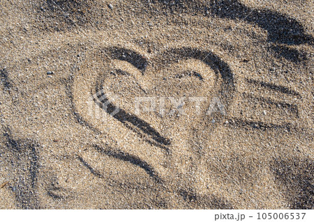 Drawing heart shape love concept on sand at the beach with vacation holiday summer travel background. Heart shape and footprint on sand. Drawing heart shape love concept on sand at the beach with vacation holiday summer travel background. Heart shape and footprint on sand. 105006537