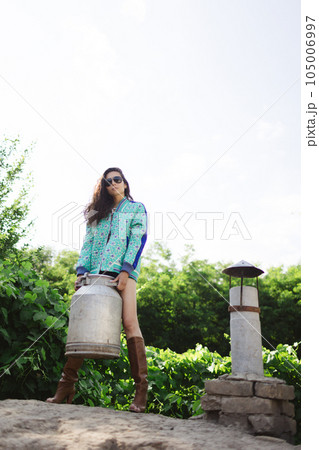 Young fashionable farmer woman posing on camera while holding milk can 105006997