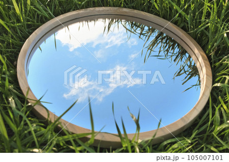 Cloudy Blue Sky Reflection in Round Wood Mirror on Summer Field with Green Grass. Nature Concept. Earth Day. Save Environment. Peace. Ecology Protection. Climate Change, Global Warming Effect Problem Cloudy Blue Sky Reflection in Round Wood Mirror on Summer Field with Green Grass. Nature Concept. Earth Day. Save Environment. Peace. Ecology Protection. Climate Change, Global Warming Effect Problem 105007101