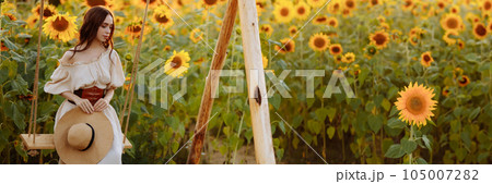 Woman in a dress in a field of sunflowers on a swing 105007282