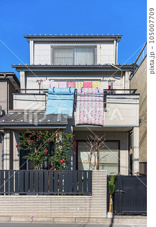 [国内] 布団をバルコニーに吊るし、太陽の光を浴びながら干しているモダンな日本家屋。 105007709