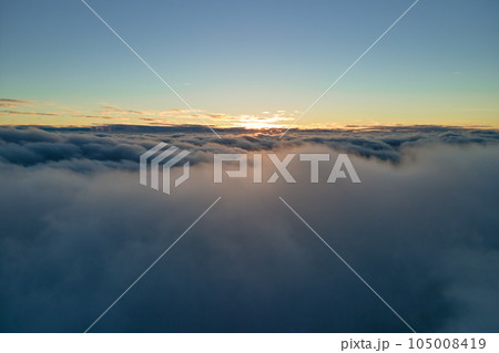 Aerial view from above at high altitude of dense puffy cumulus clouds flying in evening. Amazing sunset from airplane window point of view Aerial view from above at high altitude of dense puffy cumulus clouds flying in evening. Amazing sunset from airplane window point of view 105008419
