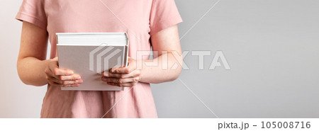 Hand holding closed paper book in hard cover. Banner background 105008716
