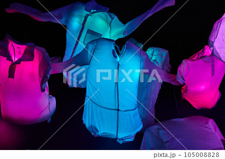 Glowing clothes of neon blue and pink hanging in the air suspended over a black background 105008828
