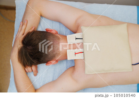 patient with an electrotherapy on the back, electrical stimulation patient with an electrotherapy on the back, electrical stimulation 105010540