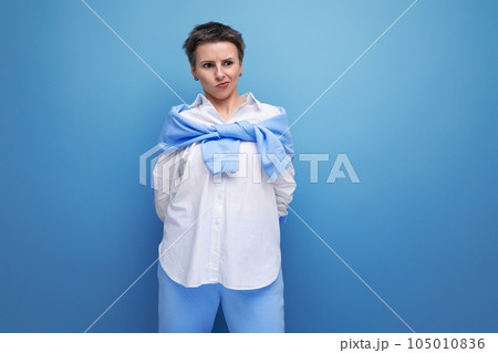 upset young dark-haired woman with sticking hair in a white shirt 105010836
