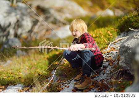 Preteen boy in red shirt is exploring nature and having fun during hiking in mountains valley on sunny day. Active leisure for energetic children. Summer outdoor recreation for kids 105010938