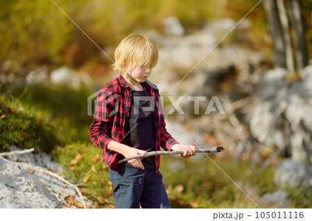 Preteen boy in red shirt is exploring nature and having fun during hiking in mountains valley on sunny day. Active leisure for energetic children. Summer outdoor recreation for kids 105011116