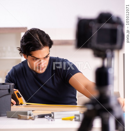 Young male repairman recording video for his blog Young male repairman recording video for his blog 105012071